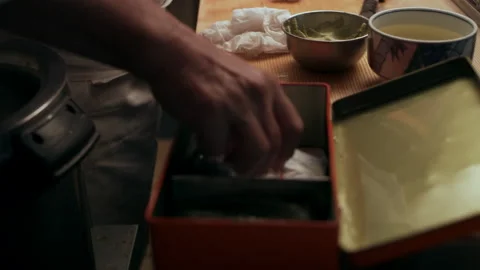 Experienced male sushi chef using sheets of nori and balls of rice to make Maki Stock Footage 199459810