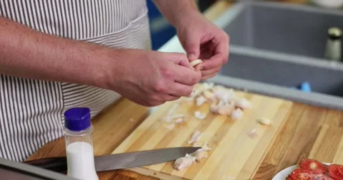 Experienced man chef removes outer layer of garlic clove Stock Footage 301080449