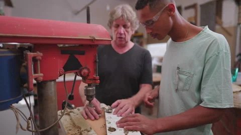 Experienced master carpenter guiding young apprentice at carpentry workshop.. Video stock 255868370