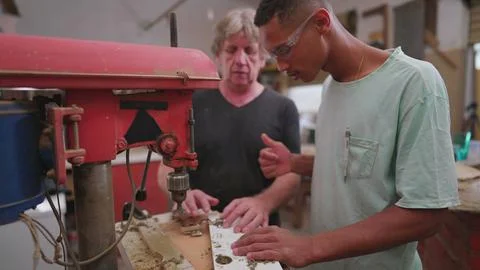 Experienced master carpenter guiding young apprentice at carpentry workshop.. Foto stock