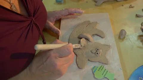 An Experienced Master Makes a Clay Toy Cat on a Wooden Board, and a Six Year Stock Footage 59127794