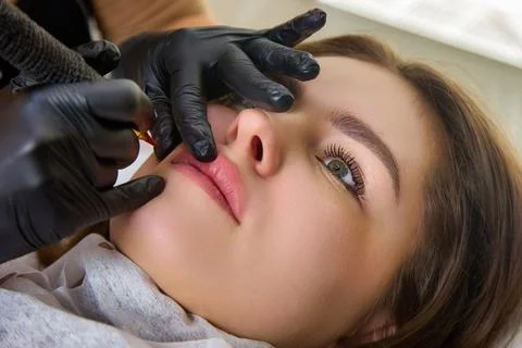 Experienced master in performs lip tattooing with professional equipment Stock Photos