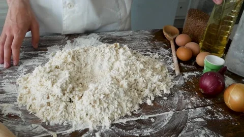 Experienced mature chef cracking egg into flour to make bread according to Stock Footage 220766833