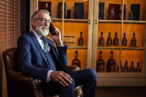 Experienced old private physician talking on smartphone with pat Stock Photos