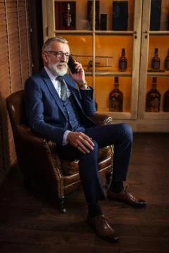 Experienced old private physician talking on smartphone with pat Stock Photos