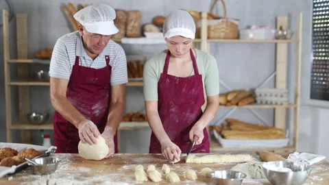 Experienced older baker and young female apprentice in striped aprons working 스톡 동영상 288798041