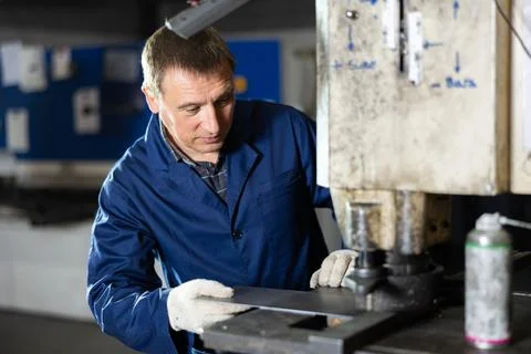 Experienced operator working on metal punching machine in workshop Stock Photos