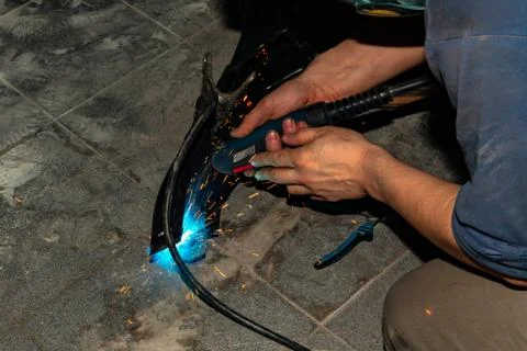 An experienced person performs work with a welding machine, fixing metal part Stock Photos