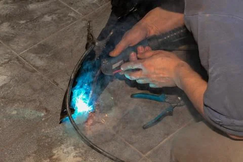 An experienced person performs work with a welding machine, fixing metal part Stock Photos