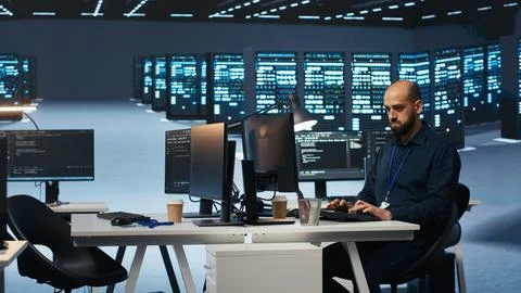 Experienced person typing code on computer monitors in data center Foto stock