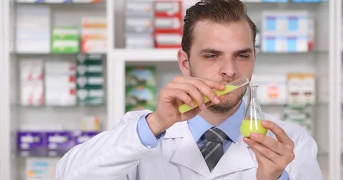 Experienced Pharmacist Analyzing in Pharmacy Laboratory a Yellow Liquid Drugs Stock Footage 70686442