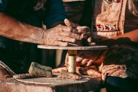 An experienced potter teaches an apprentice to work with clay and a potter's  스톡 사진