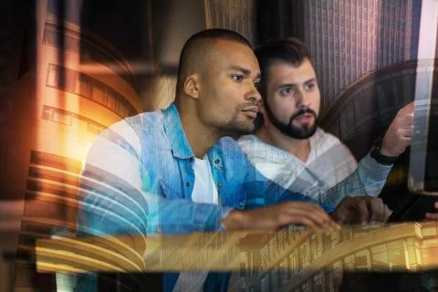 Experienced programmers looking at the screen while working together Stock-Fotos