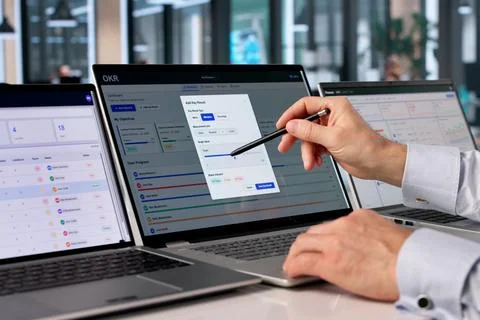 Experienced Project Manager Analyzes OKR Dashboard On Laptop For Team Progres Stock Photos