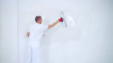Experienced repairman is plastering wall, using spatula, putty knife  Stock Footage 143761440