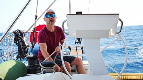 Experienced sailor trimming a sailing line on a modern yacht during an offshore Stock Footage 345653440