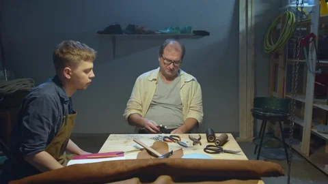 Experienced shoemaker asks student to bring tools Stock Footage 127834610
