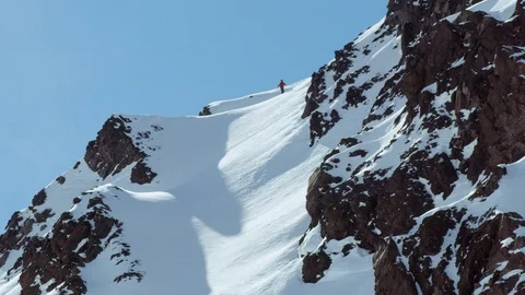 Experienced snowboarder riding down mountain summit in freeride terrain Stock Footage 121597776