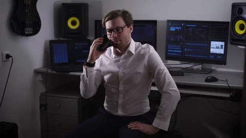Experienced software developer smiling talking on his smartphone while computers Stock Footage 72448079
