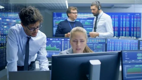 Experienced Stock Exchange Trader Consults His Apprentice at Her Workstation.  스톡 동영상 81277458