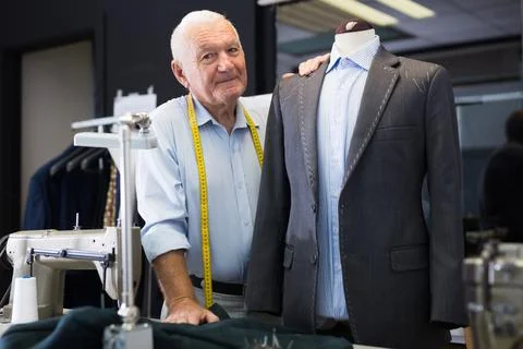 Experienced tailor threading jacket before starting work in workshop Stock Photos