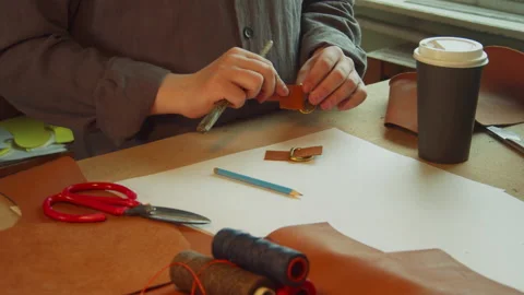 An experienced tailor in the workshop behind the workbench prepares accessories Stock Footage 143725044