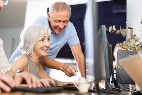 Experienced teacher of computer class assisting enthusiastic woman Fotos de archivo
