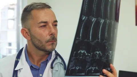 An experienced therapist looks closely at the X-Ray image Stock Footage 80996430