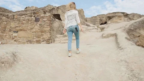Experienced tourist explores old ancient city, slowly rises up slope of white Stock Footage 105968658
