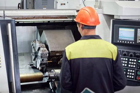 Experienced worker changing tool setup of cnc lathe machine on the factory fl Stock Photos
