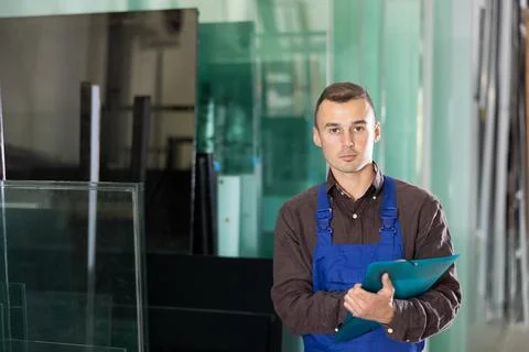 Experienced worker checks the quality of made window glass in an industrial Foto stock