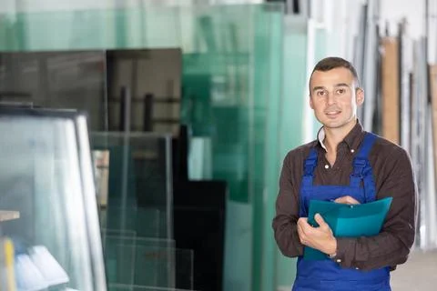 Experienced worker checks the quality of made window glass in an industrial Foto stock