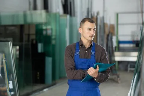 Experienced worker checks the quality of made window glass in an industrial Foto stock