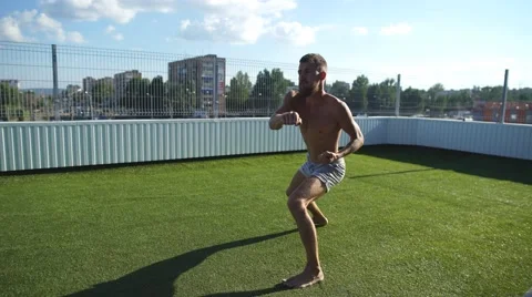 Experienced yoga master performs various yoga poses on a roof over blue sky Stock Footage 68028768