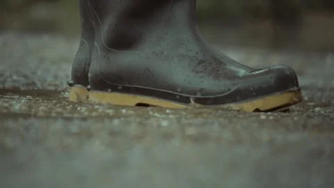 Experiencing Footsteps in a Rainy Puddle While Wearing Colorful Rubber Boots Stock Footage 310206228