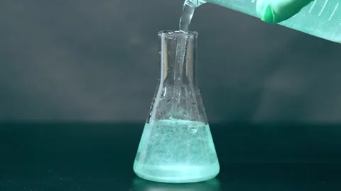 An experiment of pouring a green liquid into a flask. Lab test Vidéo 172344488