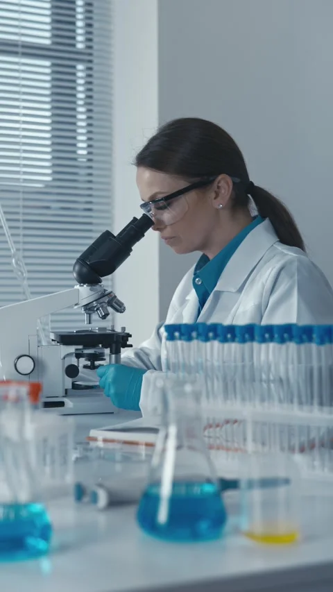 An experimental geneticist in the laboratory works with a microscope, develops Stock-Footage 266563728