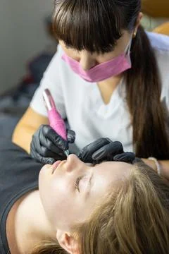 Expert applying lip permanent makeup for long-lasting enhancement in a beauty Stock Photos