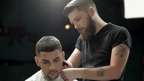 Expert barber skillfully styling men's hair and beard in a trendy barbershop Stock Footage 311673414