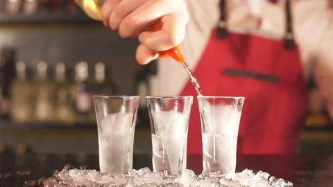 Expert barman in elegant uniform pouring vodka in frosted short glasses Stock Footage