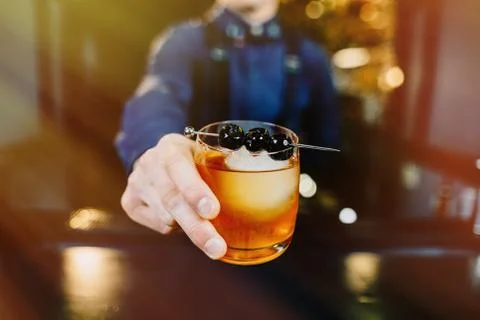 Expert Bartender is making cocktail at bar. Stock Photos