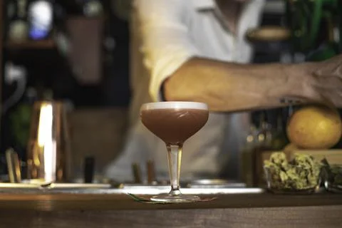 An expert bartender preparing a cocktail in a night club bar counter, view of Stock Photos