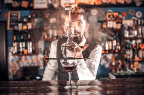 Expert bartending mixes a cocktail while standing near the bar counter in pub Foto stock