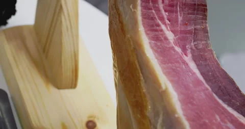 Expert chef skillfully slicing cured ham leg for culinary delicacy Video stock 303630610