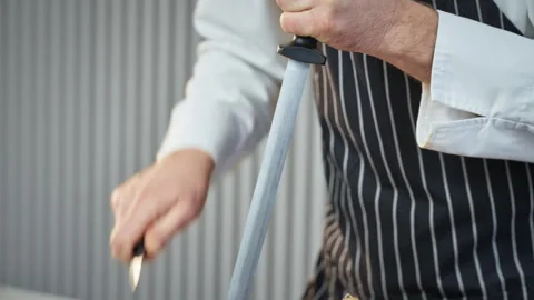 Expert chef using steel rod to sharpen culinary tools Stock Footage 324578085
