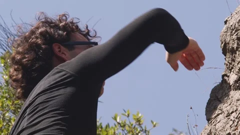 Expert Climber Engages with Challenging Rock Face: A Portrait of Focus and Stock Footage 270910391