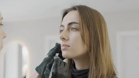 Expert cosmetologist performs slow motion permanent makeup application Stock Footage 319825623