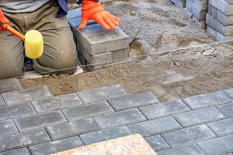 Expert craftsman laying bricks with precision while preparing a walkway in .. Stock Photos