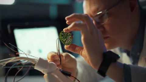 Expert in electronics repairing circuit board with precision tools in a mode Stock Footage 323767390
