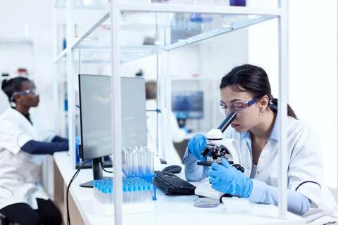 Expert in in genetics doing research using microscope Stock Photos